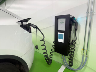 White electric car receiving power from a modern ev charging station