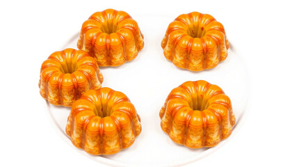 Title: Five small round cakes arranged on a white plate with a glossy golden glaze