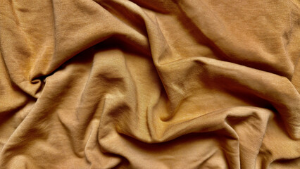 closeup caramel brown jersey fabric elegantly draped with soft wrinkles and subtle ribbed texture ideal for fashion mockups or neutral website backgrounds