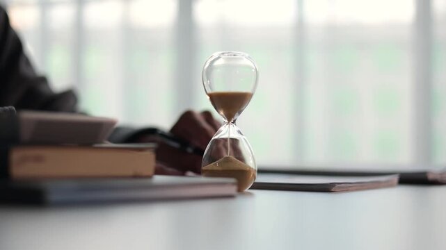 Selective focus on Sand Clocks. Businessman working at office desk. Time management concept.