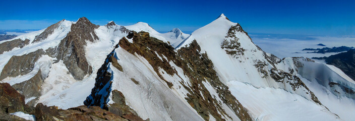 Panorama of Alpine glaciers and snow covered peaks with steep ridges and high altitude terrain. Mountain environment showing ice fields, climate conditions, rugged geology, European Alps landscape, na
