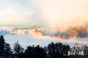 Mariä Himmelfahrt Kirche auf der Insel im See Bled im dichten Nebel bei Sonnenaufgang, goldener...
