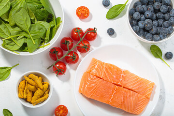 Healthy anti inflammatory diet food ingredients white background salmon blueberry vegetables spinach