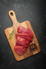 Raw beef steaks cooking preparation rosemary pepper red meat cutting board