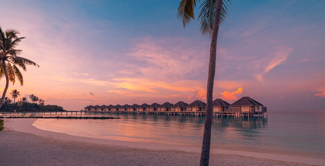 Stunning Maldives resort travel vacation panoramic background with beautiful serene sunset ocean shore palm trees horizon luxury water villas tropical paradise relaxation scenery. Tourism panorama