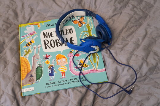 Children's book with cartoon insects and blue Sonic headphones on a quilted blanket