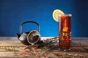 Red Tea With Ice Served on Wooden Table With Tea Pot and Strainer