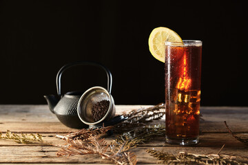 Red Tea With Ice Served on Wooden Table With Tea Pot and Strainer