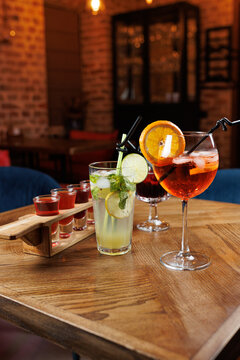 Enjoying a variety of refreshing drinks on a wooden table in a cozy restaurant setting with a lively atmosphere during the evening