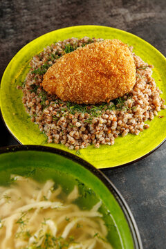 Enjoying a hearty meal featuring buckwheat with a breaded chicken cutlet served with a side of soup