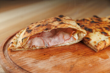 Delicious stuffed flatbread with meats cooked on wooden board in a kitchen setting