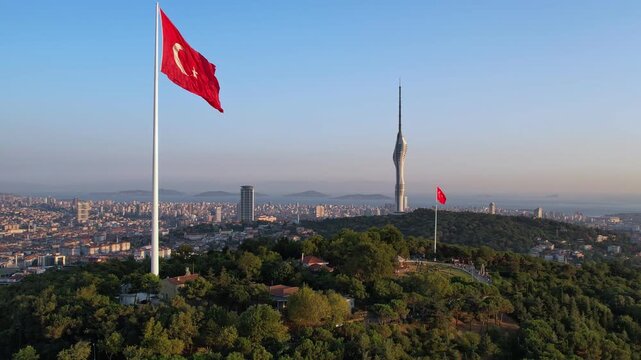Drone footage showing a large Turkish flag on Camlica Hill with Camlica Tower and the vast Istanbul skyline in clear daylight.