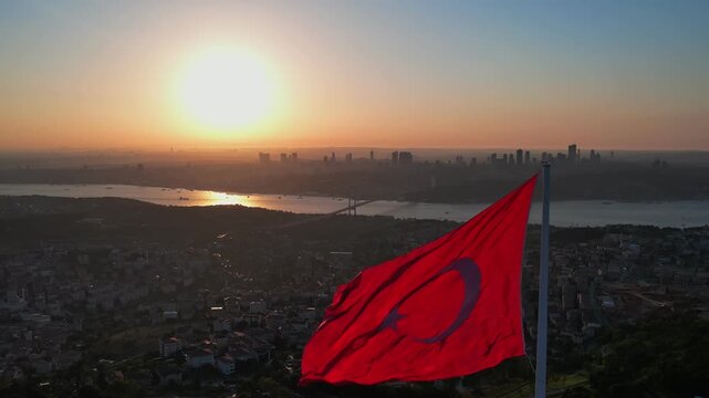 Drone footage showing Camlica Mosque, the large Turkish flag, the Bosphorus and Istanbul skyline illuminated by the warm light of the sunset.