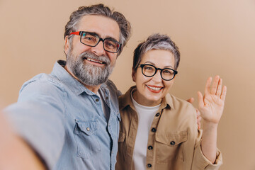 Happy senior couple waving during selfie