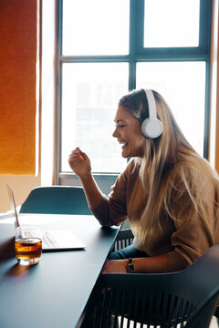 Smiling woman using laptop with headphones during video call in bright room