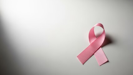 Empowering symbol of unity A poignant pink ribbon, universally recognized for breast cancer awareness, gently illuminated on a clean surface, signifying support and health advocacy for a vital cause