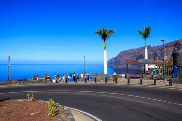 Tourists at viewpoint Mirador Archipenque looking towards vertical cliffs of the Giants (Acantilados de Los Gigantes) and Atlantic Ocean at Canary Island Tenerife, Spain