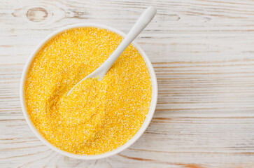Bowl of Yellow Cornmeal on Wooden Surface