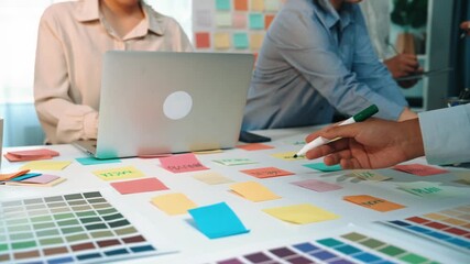 A vibrant workspace featuring a laptop and coffee cup surrounded by colorful sticky notes and color swatches, representing a collaborative team brainstorming session. SACTR
