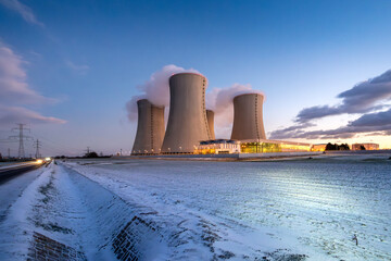 Cooling towers of the nuclear power plant. Large smoking cooling towers in the evening in winter at sunset.