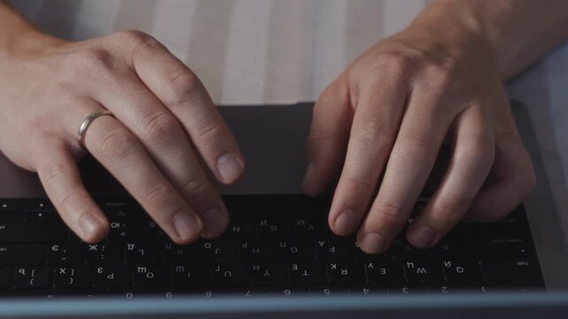 Centered close up of male hands typing on a laptop keyboard. Even lighting, relaxed posture and focused digital work during a quiet indoor session. High quality 4k footage