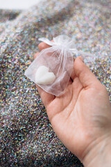 Hand holding sachet with heart-shaped soap over winter sweater.