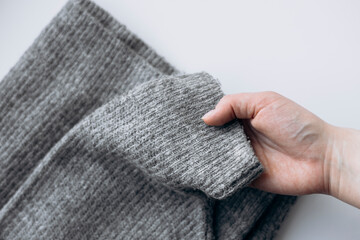 Close-up of a woman holding a soft gray sweater, isolated on white background.