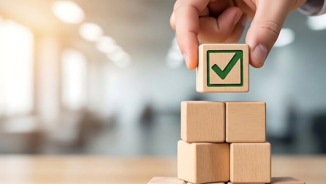 Hand placing final wooden block with green checkmark on stacked cubes