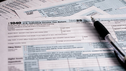 Completing U.S. individual income tax return for the year 2025 with documents and pen on a table