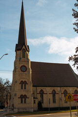 Obraz premium Yellow stone Gothic church in the United States against a clear blue sky. Historic religious architecture, faith and heritage concept