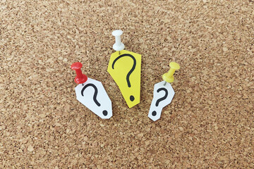 Question marks on papers pinned on cork board