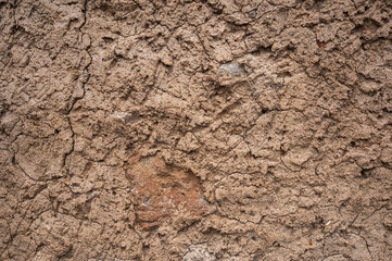 Alte Lehmwand nach historischer Bauweise aus Afrika. Risse und Baumaterial sind erkennbar.