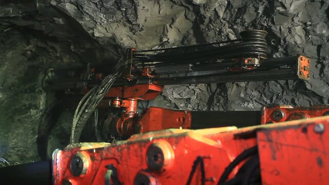 A drilling rig drills into rock in a mine