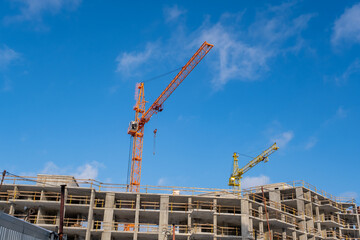 High-Rise Building Construction Site with Tower Cranes and Concrete Structure Under Blue Sky