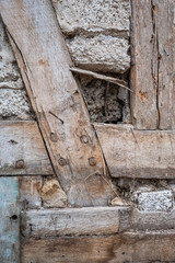 Obraz premium Alter Hauswand mit Brettern, Steinen und Beton. Historisches Bauwerk mit erkennbaren Altersspuren.