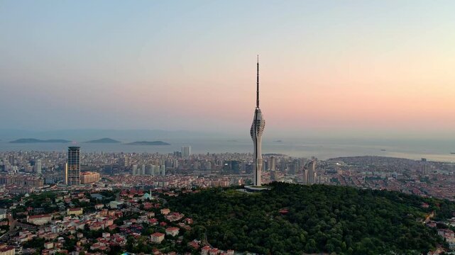 Drone footage showing Camlica Tower rising above Istanbul&rsquo;s skyline, surrounded by forests, residential areas and the Marmara Sea under warm sunset light.