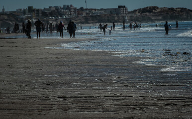 playa de dia un dia de verano con la gente paseando por la costa