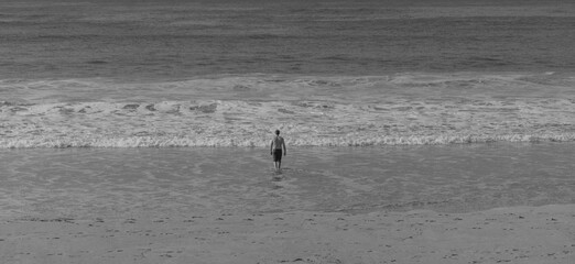 Abstract Black and White Image of Walking into Water. Black and white image of a person walking into the ocean, creating a minimalist and emotional scene.