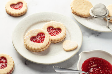 Linzer cookies in shape of heart with jam on white marble background. Mother's day, Valentine's day. Homemade present