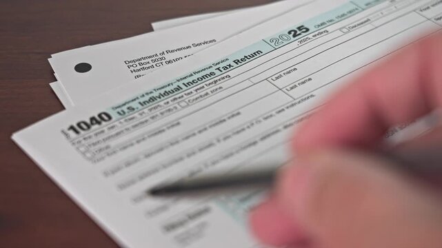 The tax return form 1040 is displayed and person is going over details.. This form is used for filing individual income taxes in the U.S. for the year 2025.