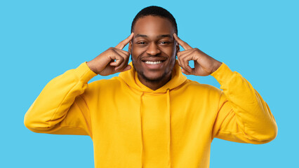 Brainwork. Cheerful African American Man Pointing At His Forehead Having Creative Thoughts And Ideas Posing Smiling To Camera Standing Over Blue Studio Background. Panorama