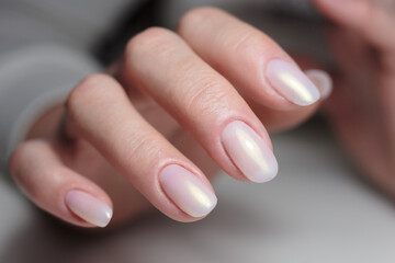 Close up of hands with polished nails showing light colors in a beauty salon setting.
