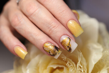 Elegant yellow nails with butterfly designs on fingers in a beauty studio 
