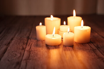 serene grouping of lit candles on rustic wooden surface casting warm, soft glows with flickering...