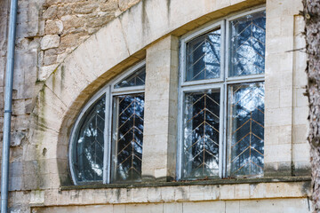 Arched stone building window with reflective glass and geometric patterns