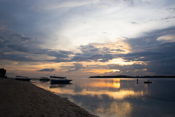 beautiful dramatic landscape of sunset on sea beach with silhouette of boat