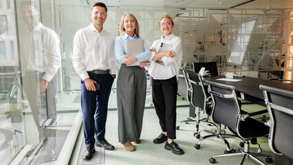 Three team members pose in modern office space