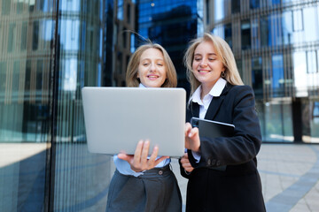 Two women work together outside a modern office building