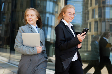 Business women walking and using phone outside office