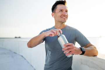 Man enjoys drink while standing outdoors near railing